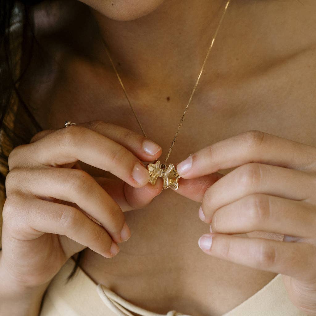 A person wearing the Polly Star Locket Necklace and opening the locket.