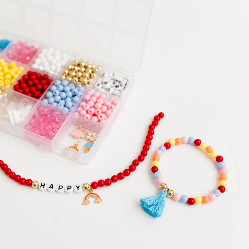 A pastel and red beaded bracelet next to a red beaded bracelet with the word "Happy" and a rainbow charm.