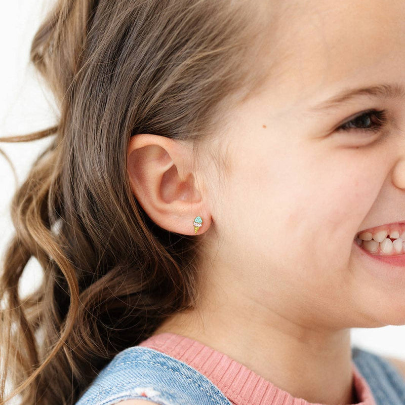 A young girl wearing the Ice Cream Stud Earrings while smiling to the side.