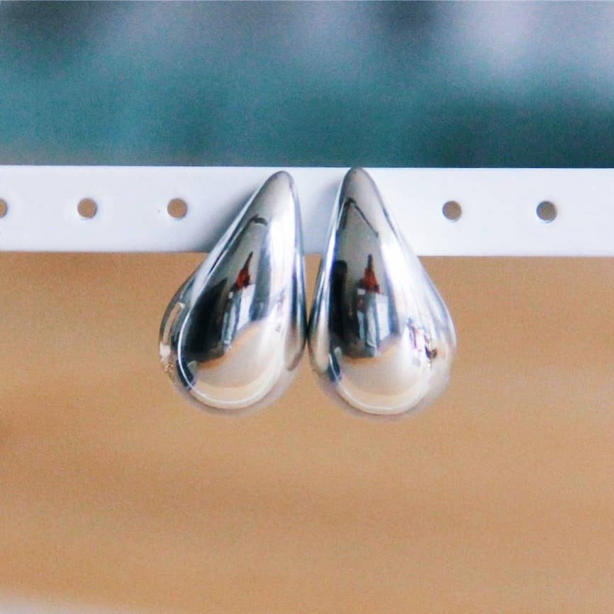 Two Glossy Drop Earrings Hanging from a white post.