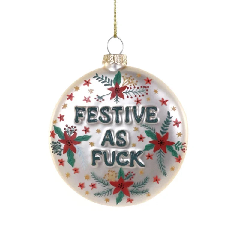 A circular white glass ornament decorated with holiday florals and the words "Festive as F*ck" uncensored.