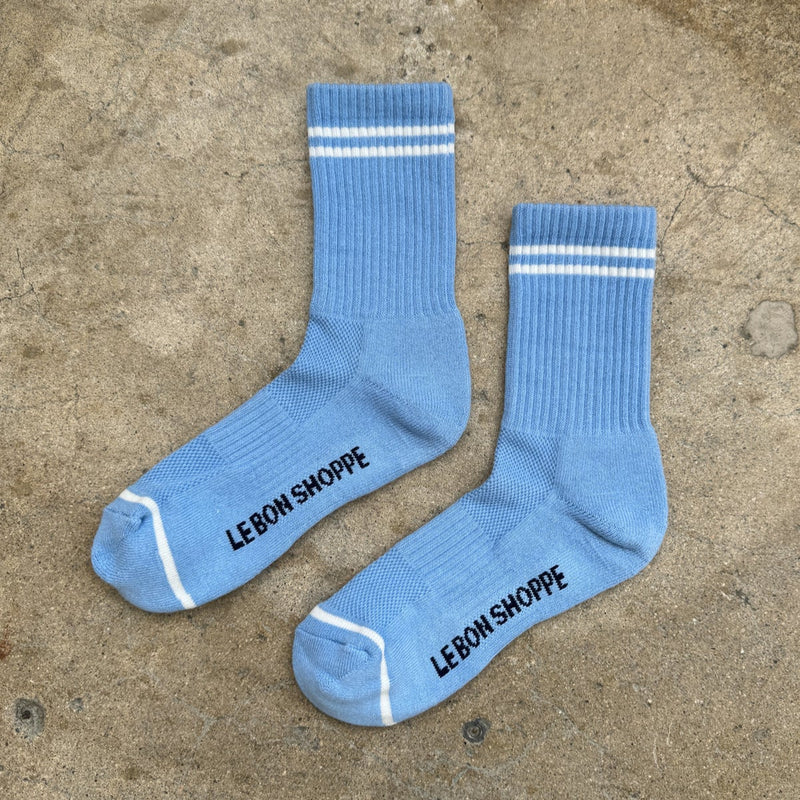 A pair of light blue long crew length socks with two white stripes above the ankle and one white stripe below the toe.