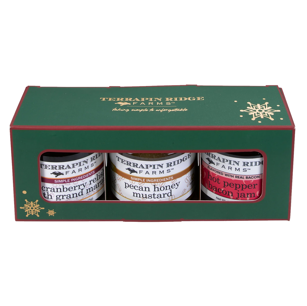 A green and red box filled with jars of Cranberry Relish with Grand Marnier, Pecan Honey Mustard and Hot Pepper Bacon Jam.