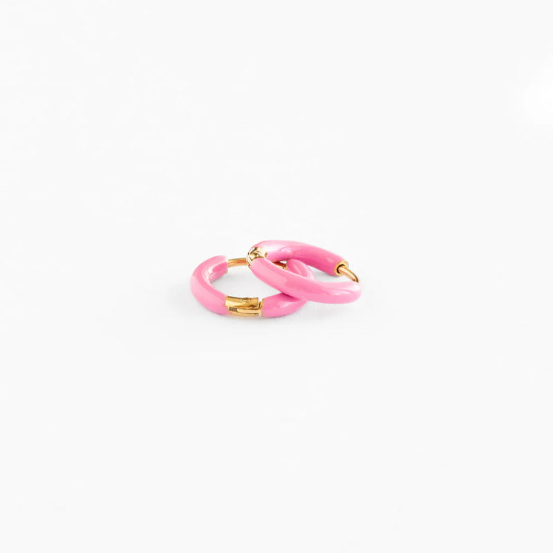 A pair of pink enamel huggie hoops with gold plated hardware.