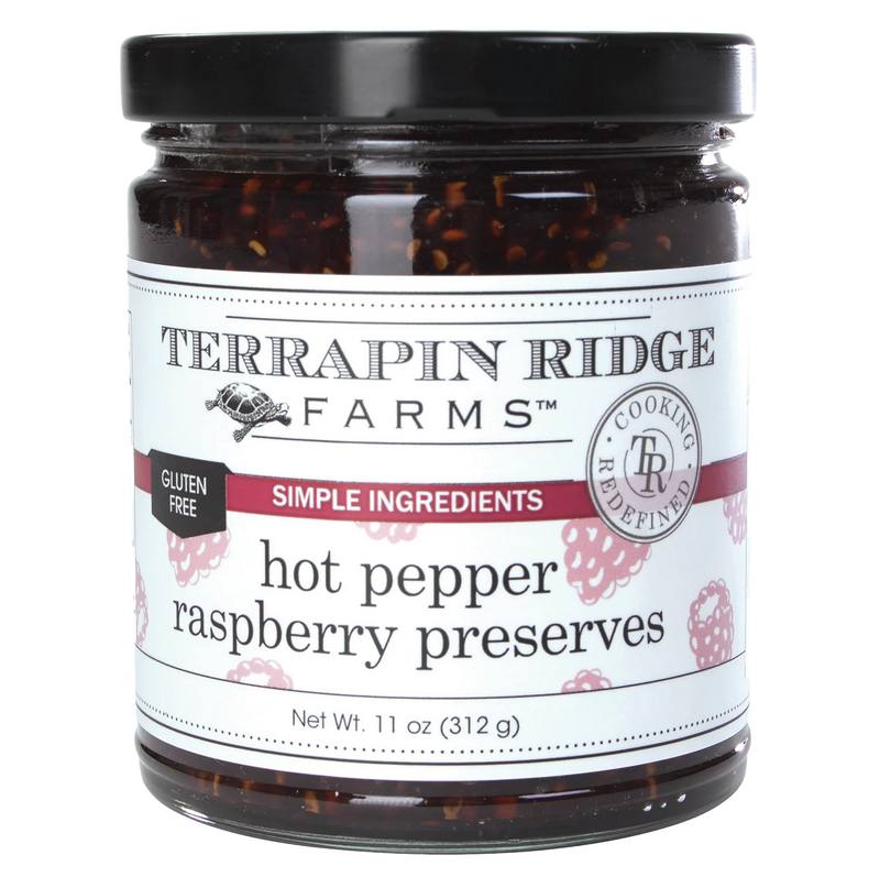 A clear jar of Hot Pepper Raspberry Preserves with a black lid.