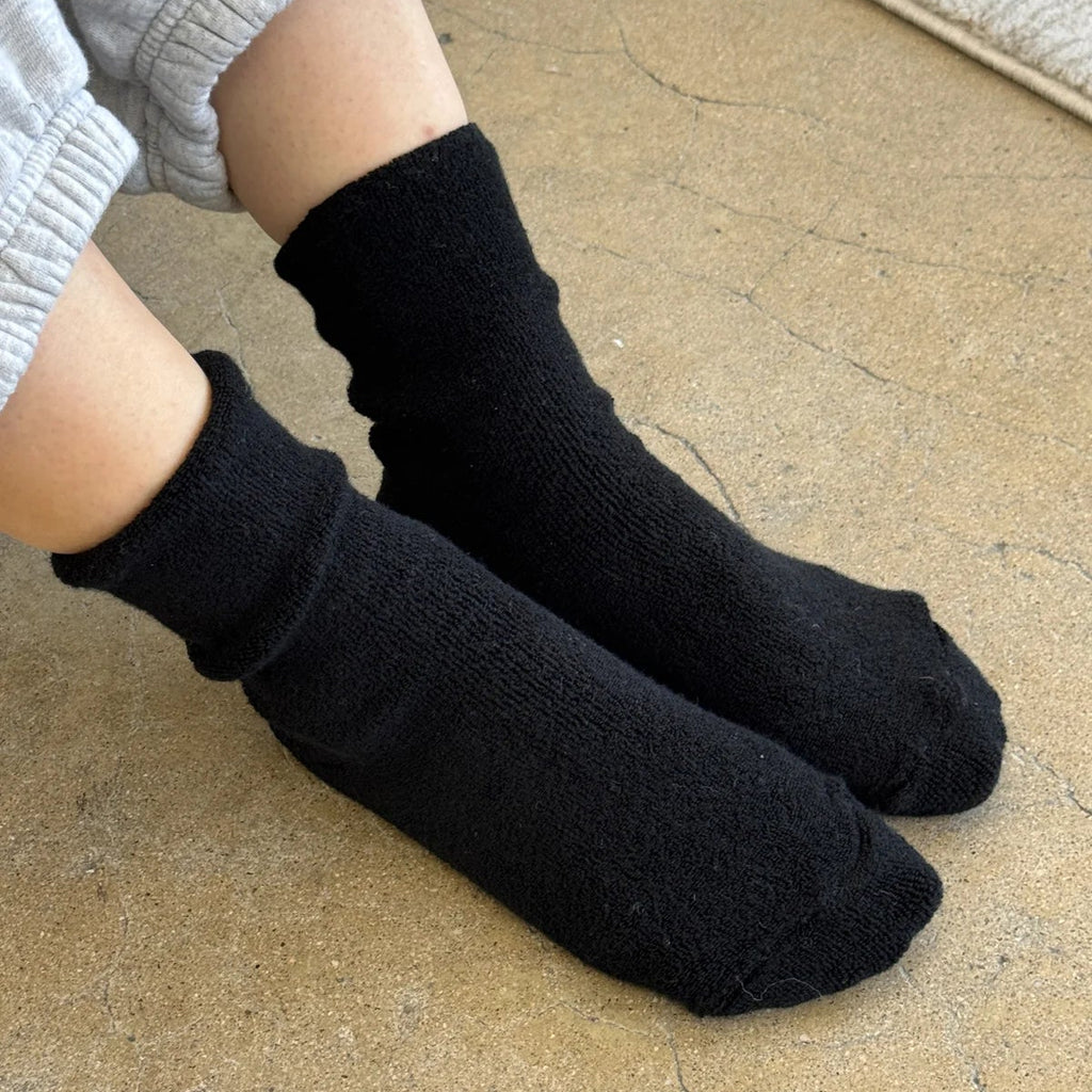 A person wearing Cloud Socks in Jet Black with gray sweatpants.