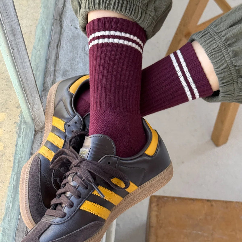 A person wearing the Boyfriend Socks in Maroon with brown and yellow gym shoes and green sweatpants.