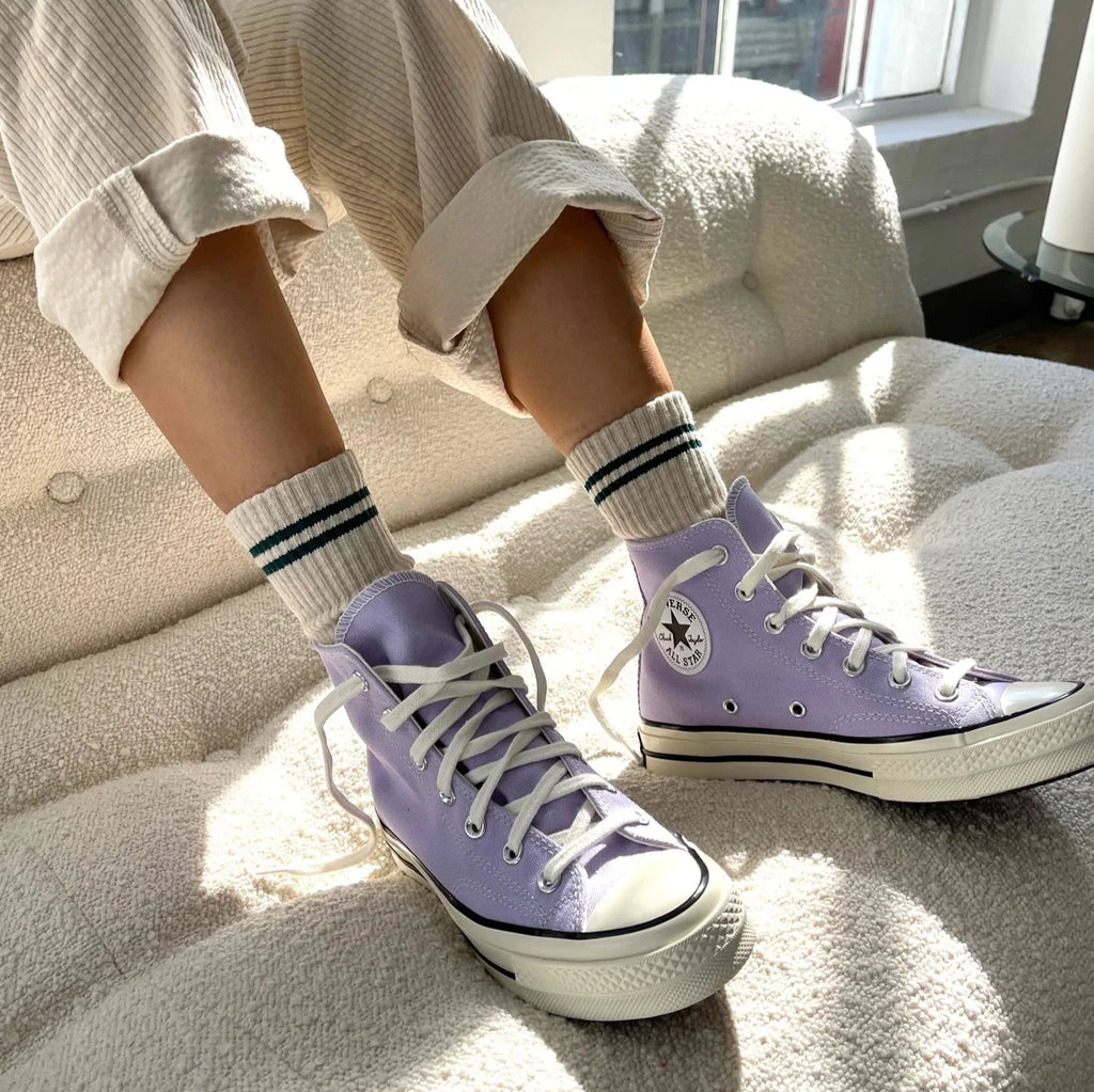 A person wearing the Boyfriend socks in Oatmeal with cream corduroy pants and lavender converse shoes.