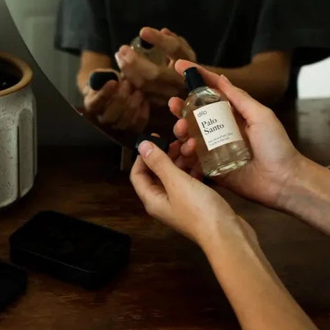 A pair of hands spraying Palo Santo in front of their vanity.