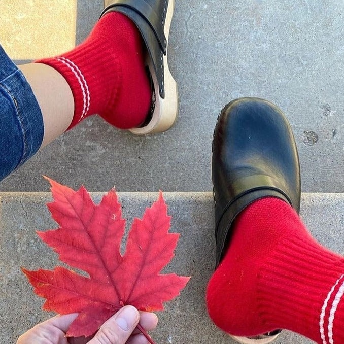 A person wearing the Boyfriend Socks in Red with black clogs and blue jeans.