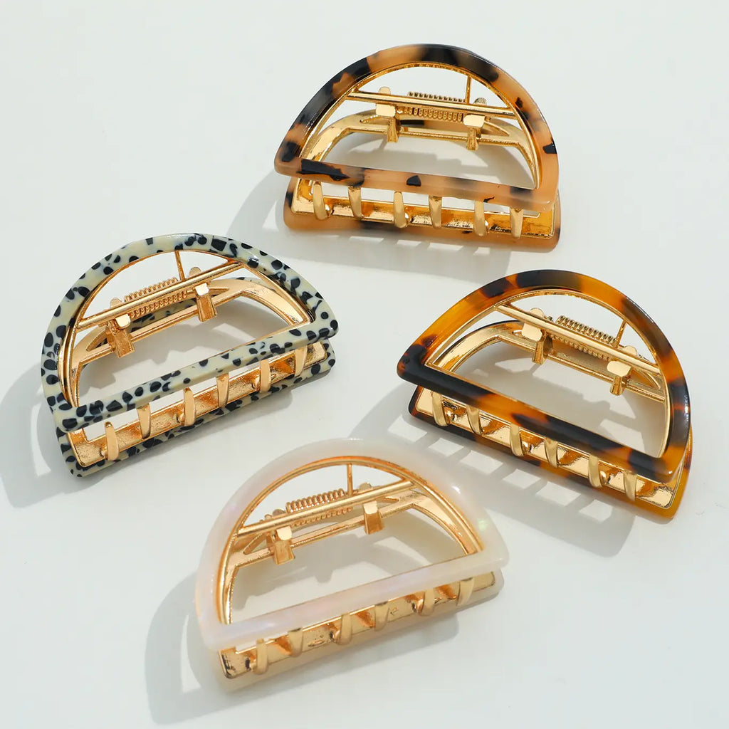 Four half circle shaped hair clips with different patterns.