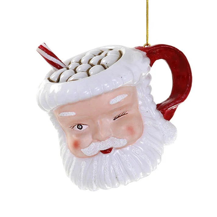 A smiling and winking light skinned Santa Claus coffee mug ornament filled with  hot chocolate, marshmallows, and a candy cane.