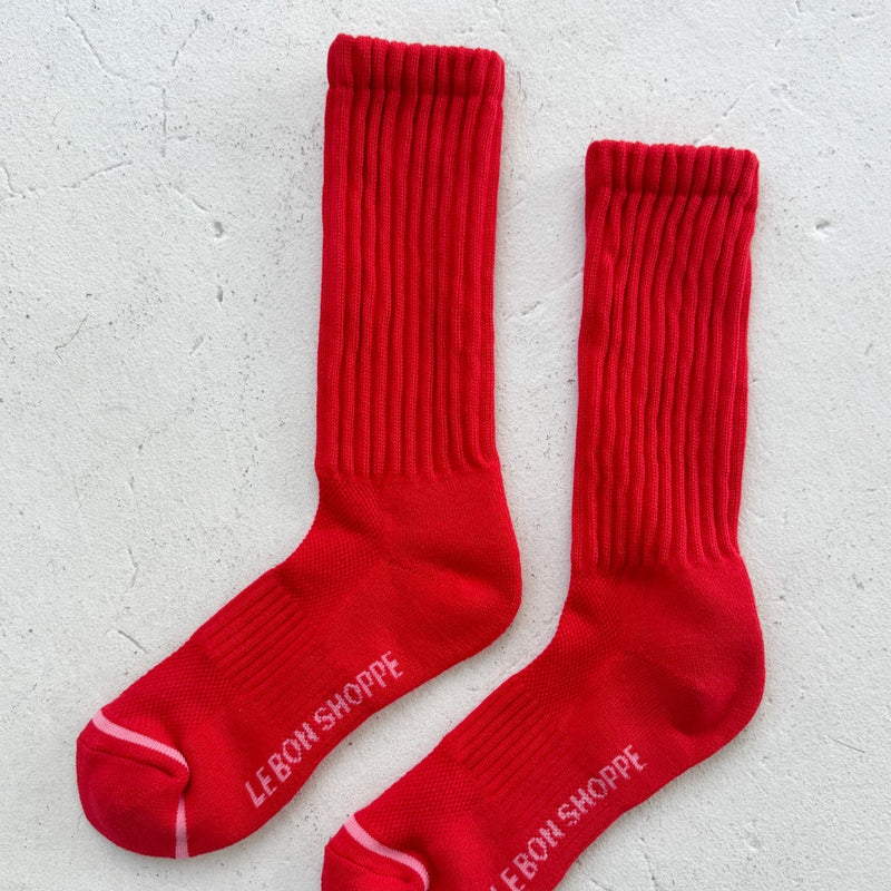 A pair of long crew length socks with a pink stripe at the toe and the words "Le Bon Shoppe" in pink below the foot.