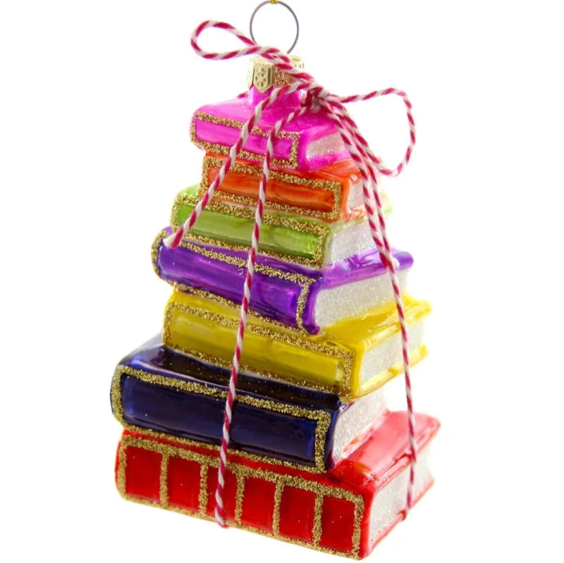 A colorful stack of glass books detailed with gold glitter on the spine and tied together with red and white twin and a gold cord for hanging as an ornament.