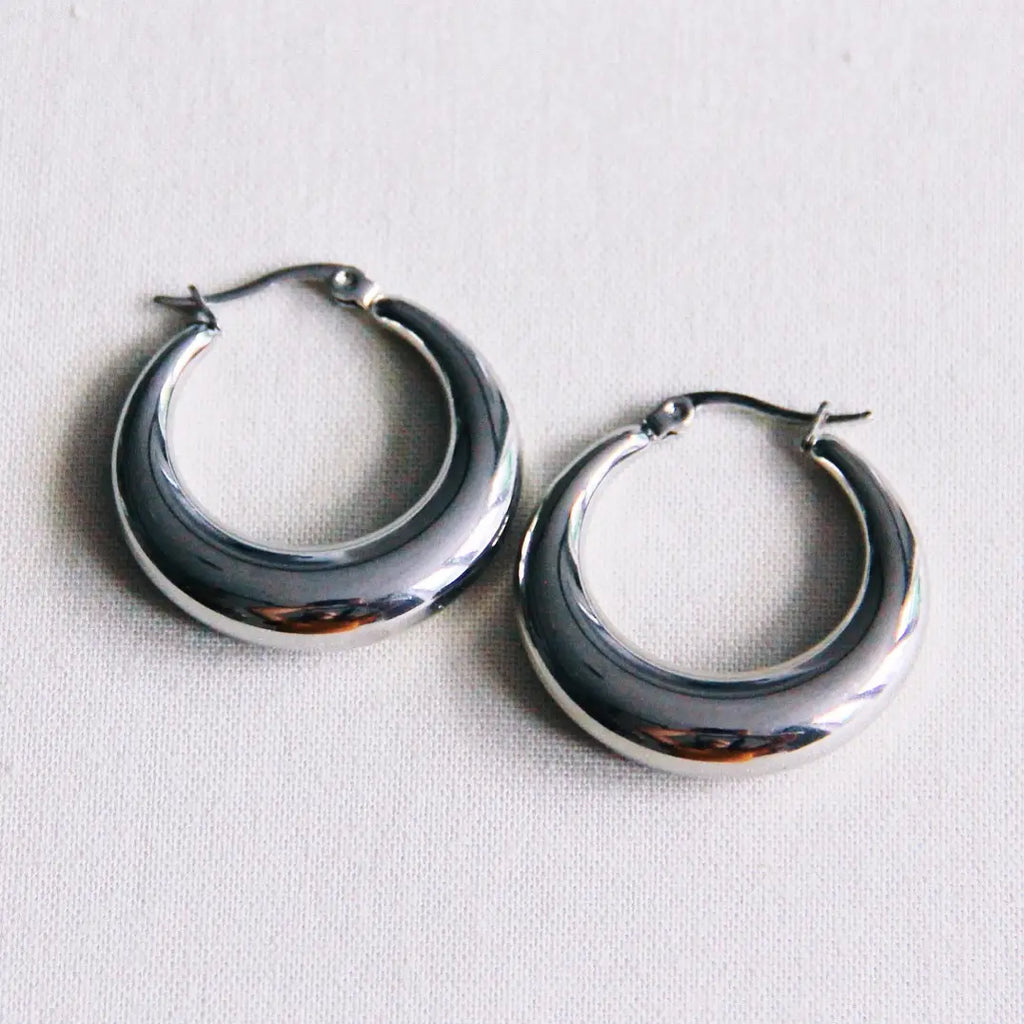 A pair of silver stainless steel hoops that flare wider at the bottom.