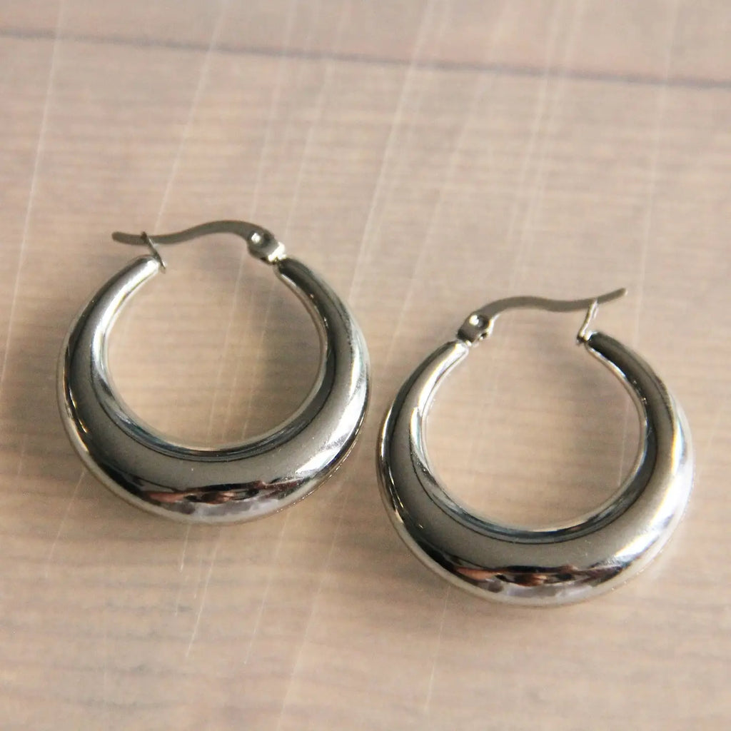 A pair of silver stainless steel hoops that flare wider at the bottom.