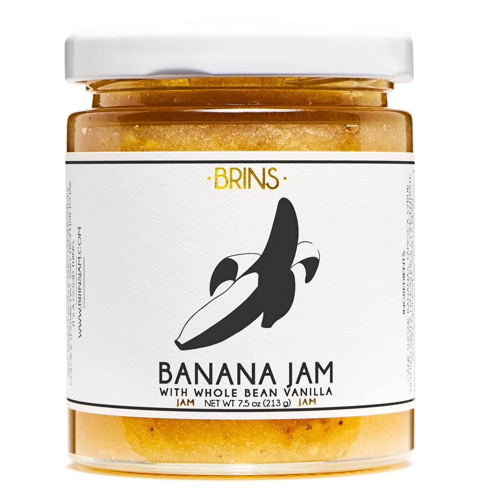 A clear glass jar of Banana Jam with a white lid.