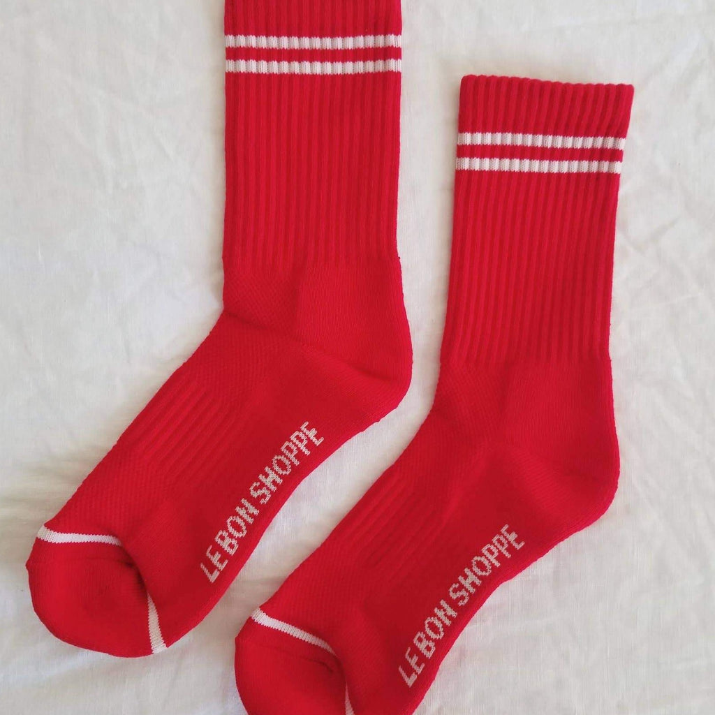 A pair of long red socks with white stripes above the ankle and at the toe.