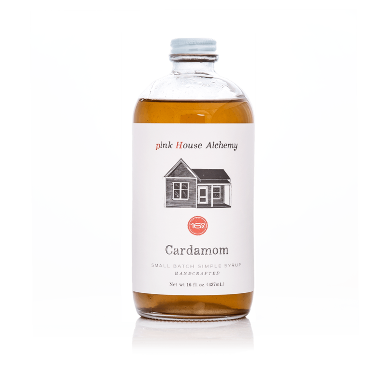 A clear glass bottle of amber-colored Cardamom Simple Syrup.